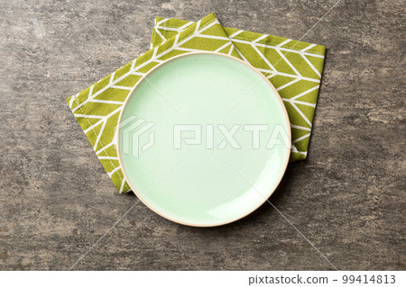 Top view on colored background empty round green plate on tablecloth for food. Empty dish on napkin with space for your design Top view on colored background empty round green plate on tablecloth for food. Empty dish on napkin with space for your design 99414813