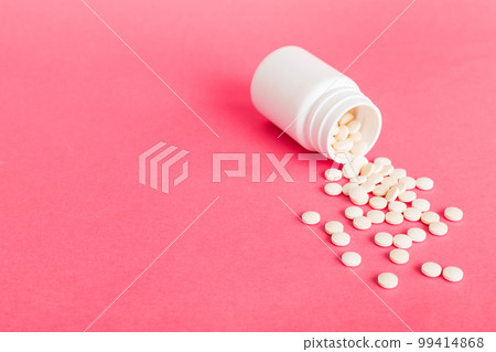 Medicine bottle and white pills spilled on a light background. Medicines and prescription pills flat lay background. White medical pills and tablets spilling out of a drug bottle Medicine bottle and white pills spilled on a light background. Medicines and prescription pills flat lay background. White medical pills and tablets spilling out of a drug bottle 99414868