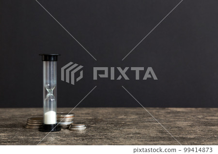 Deadline and time is money concept with hourglass and US coins currency. sand clock time for saving concept Deadline and time is money concept with hourglass and US coins currency. sand clock time for saving concept 99414873