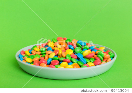 Multicolored candies in a bowl on a colored background. birthday and holiday concept. Top view with copy space 99415004