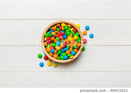 Multicolored candies in a bowl on a colored background. birthday and holiday concept. Top view with copy space Multicolored candies in a bowl on a colored background. birthday and holiday concept. Top view with copy space 99415051