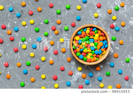 Multicolored candies in a bowl on a colored background. birthday and holiday concept. Top view with copy space 99415053