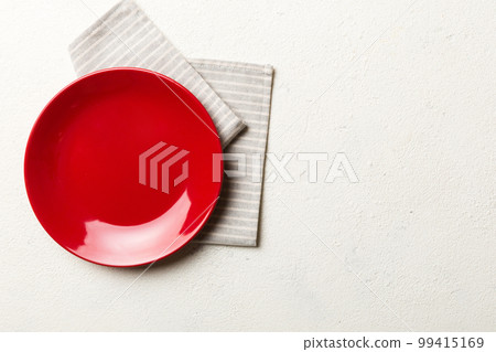 Top view on colored background empty round red plate on tablecloth for food. Empty dish on napkin with space for your design 99415169
