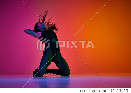 Self-expression through movements. Young woman dancing high heel dance style over gradient pink orange studio background in neon light Self-expression through movements. Young woman dancing high heel dance style over gradient pink orange studio background in neon light 99415455