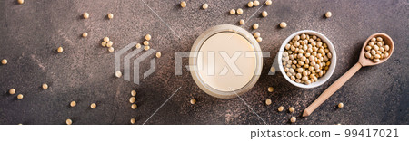 Glass of soy milk and soy beans on the table. Vegetable protein. Top view. Web banner 99417021