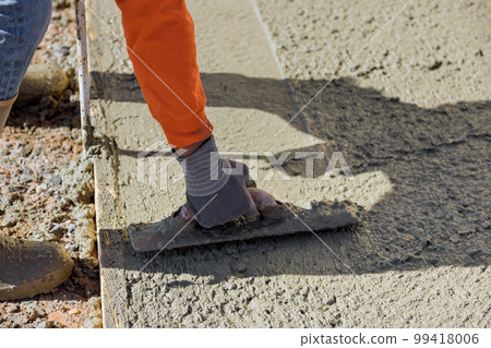 After pouring concrete worker uses trowel to plaster wet concrete cement floor 99418006