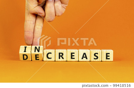 Increase or decrease symbol. Concept words Increase and Decrease on wooden cubes. Businessman hand. Beautiful orange table orange background. Business increase or decrease concept. Copy space. 99418516