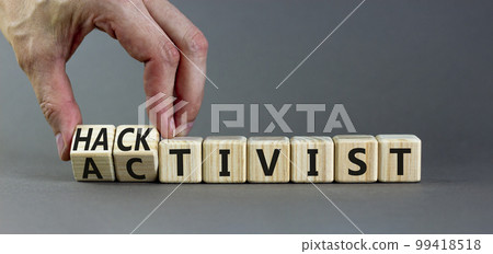 Activist or hacktivist symbol. Businessman turns wooden cubes and changes the word Activist to Hacktivist. Beautiful grey table grey background, copy space. Business activist or hacktivist concept. 99418518