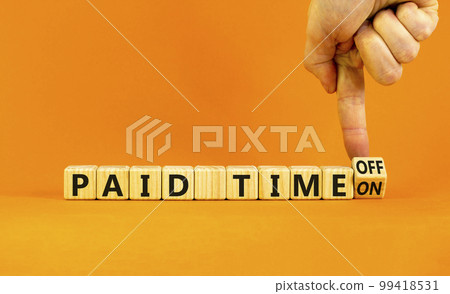 Paid time off or on symbol. Businessman turns a wooden cube and changes words 'paid time on' to 'paid time off'. Beautiful orange background. Business and paid time off or on concept, copy space. 99418531