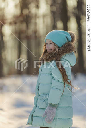 girl in a turquoise squat and a hat in the winter forest girl in a turquoise squat and a hat in the winter forest 99418661