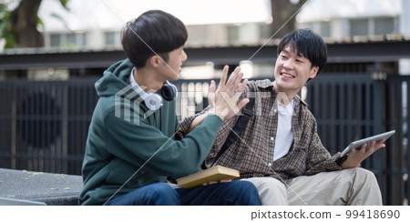 Two young Asian male college students discussing and working on their school project together 99418690