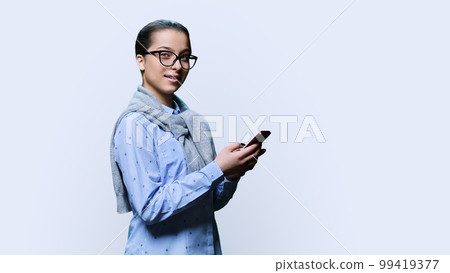 Young female with smartphone, looking at camera on white background 99419377