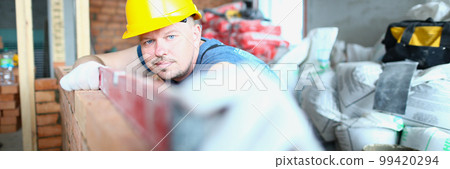 Builder carefully places red brick on masonry Builder carefully places red brick on masonry 99420294