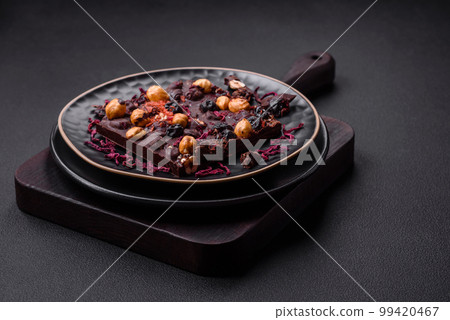 Handmade chocolate with berries, nuts and spices on a dark background Handmade chocolate with berries, nuts and spices on a dark background 99420467