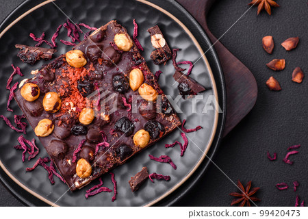 Handmade chocolate with berries, nuts and spices on a dark background 99420473