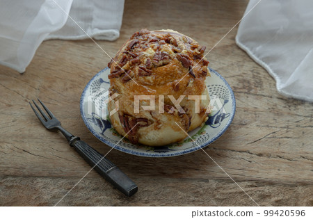 Caramel Pecanbon topped with caramel frosting and pecans served with Metal fork on old rustic wooden background. Caramel Pecanbon topped with caramel frosting and pecans served with Metal fork on old rustic wooden background. 99420596