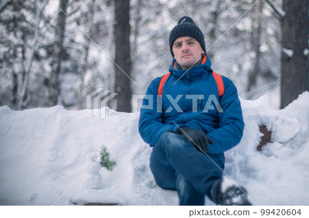 Man in winter jacket walking in snowy winter forest 99420604