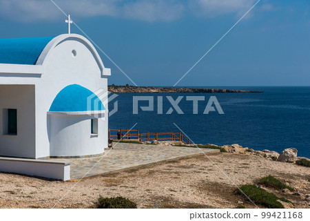 Traditional Greek white chapel with a blue roof on the seaside. Agioi Anargyroi chapel, Cyprus 99421168