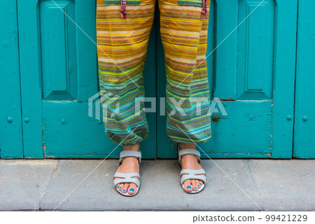 Foot of a woman in sandals. Colorful hippie pants Foot of a woman in sandals. Colorful hippie pants 99421229