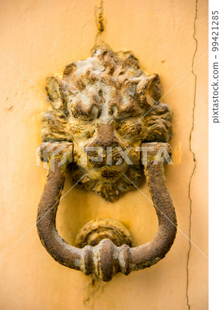 Close-up view of ancient rusty lion head shaped knocker Close-up view of ancient rusty lion head shaped knocker 99421285