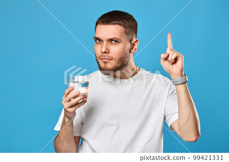 man in white t-shirt with drinking glass of water pointing up on 99421331