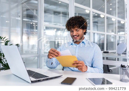 Young successful businessman inside office working with laptop, man received good news notification mail, hispanic man reading news and smiling at workplace, happy with achievement result. Young successful businessman inside office working with laptop, man received good news notification mail, hispanic man reading news and smiling at workplace, happy with achievement result. 99421779