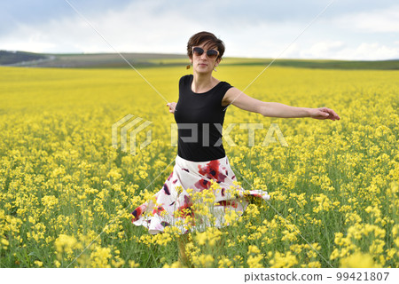 Hipster girl walking through a canola field. Freedom concept 99421807