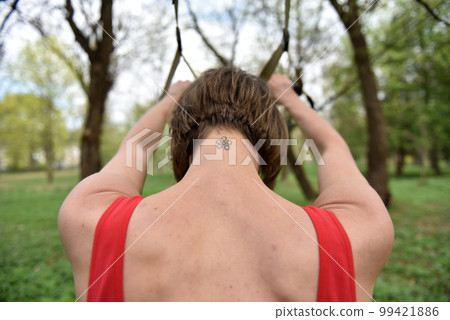 Young woman does suspension training with fitness straps in the outdoors 99421886