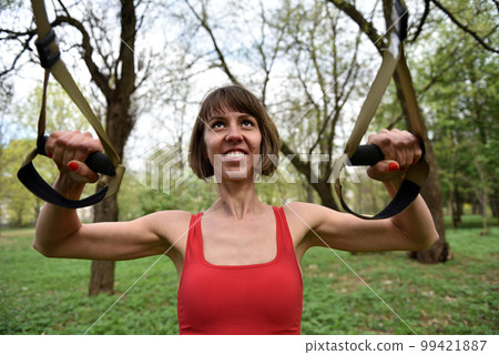 Woman doing arms biceps curl training with trx fitness straps Woman doing arms biceps curl training with trx fitness straps 99421887