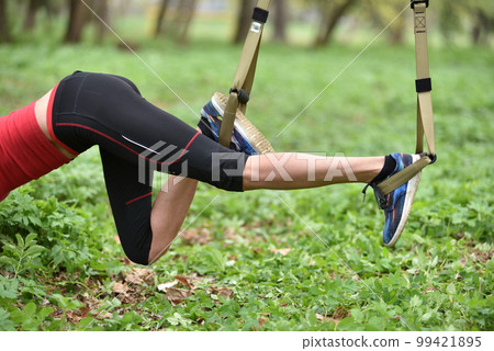Beautiful young woman doing TRX exercise with suspension trainer sling in the outdoors 99421895