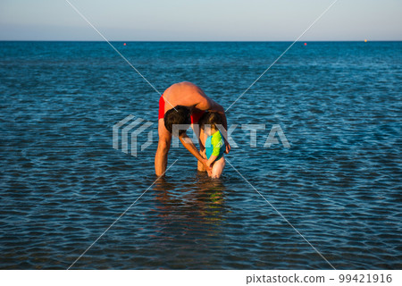Father and daughter playing together in the sea water Father and daughter playing together in the sea water 99421916