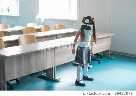 Caucasian schoolgirl wearing virtual reality glasses in the classroom. Caucasian schoolgirl wearing virtual reality glasses in the classroom. 99422078