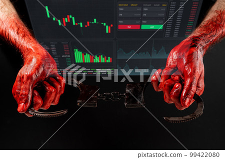A man with blood-stained hands holding handcuffs. financial crime. Stock charts on a virtual screen. 99422080