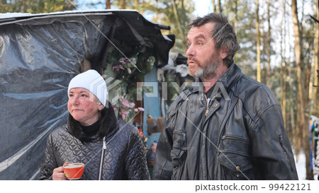 A homeless man and woman giving an interview in the winter in the woods. A homeless man and woman giving an interview in the winter in the woods. 99422121