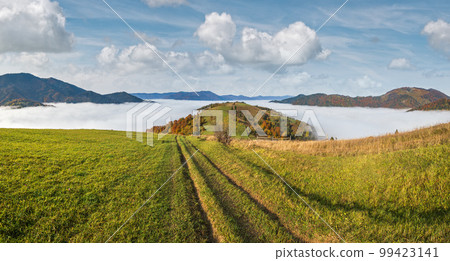 Morning foggy clouds in autumn mountain countryside.  Ukraine, Carpathian Mountains, Transcarpathia. Peaceful picturesque traveling, seasonal, nature and countryside beauty concept scene. 99423141