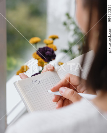 view from back, woman writes notes in notebook or diary. mental health care, psychotherapy view from back, woman writes notes in notebook or diary. mental health care, psychotherapy 99423335
