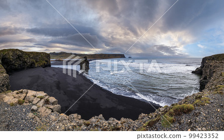 Picturesque autumn evening view to Reynisfjara ocean  black volcanic sand beach and rock formations from Dyrholaey Cape, Vik, South Iceland. Mount Reynisfjall on the background. 99423352