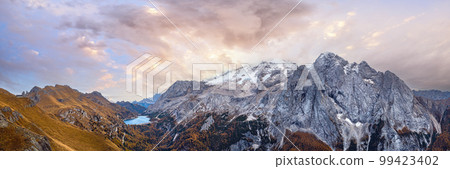 Autumn Dolomites mountain scene from hiking path betwen Pordoi Pass and Fedaia Lake, Italy. Snowy Marmolada Glacier and Fedaia Lake in far. 99423402