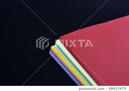 Multicolored sheets of paper on a black background. Colored office paper. A pack of colored paper. Multicolored sheets of paper on a black background. Colored office paper. A pack of colored paper. 99423479