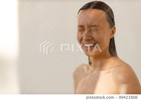 Young woman under the trickles of water in pleasure shower. Beautiful girl under the spray of water. Wet happy face Young woman under the trickles of water in pleasure shower. Beautiful girl under the spray of water. Wet happy face 99423806