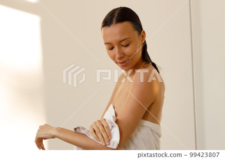 Beautiful young woman wrapping herself in white bath towel in shower stall. Hygiene, freshness and healthy cosmetic body care 99423807