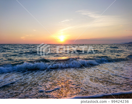 Orange sunset on sea shore with waves, Greece 99424236