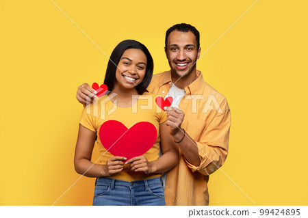 Smiling young african american lady and boyfriend holding hearts in hands, enjoy relationships 99424895