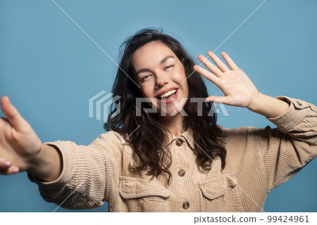 Happy pretty millennial european female student taking selfie and waving hand at camera 99424961