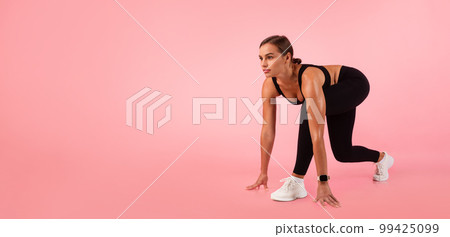 Motivated Woman Standing In Crouch Start Position Over Pink Background In Studio 99425099