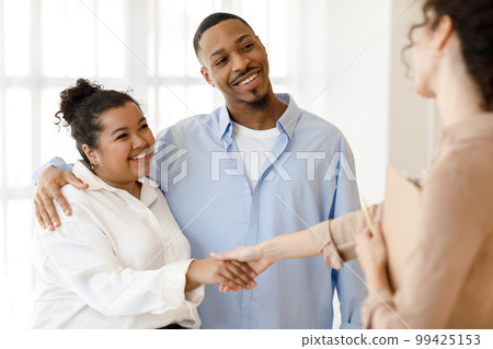 Happy black couple shaking family counselor hand, successful marital therapy Happy black couple shaking family counselor hand, successful marital therapy 99425153