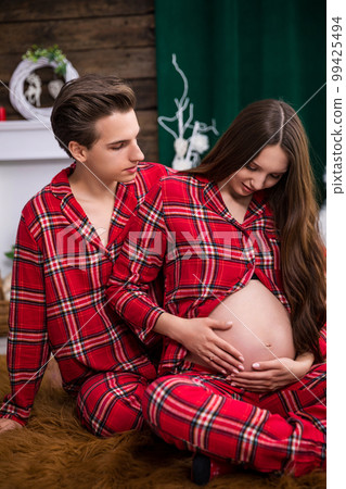 Close-up of an expecting couple sitting on the carpet 99425494