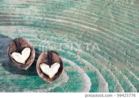 Two white hearts made of walnut halves on wooden background turquoise color, copy space. 99425776