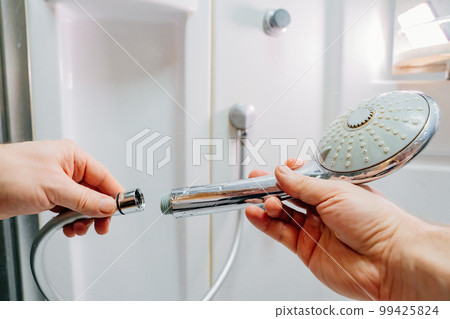 men's hands screw the shower head onto a new hose. men's hands screw the shower head onto a new hose. 99425824