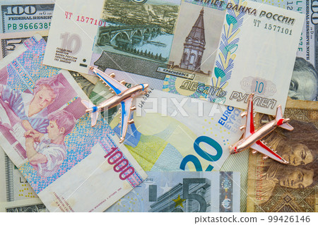 Colorful flat lay of world currencies including euros, Russian ruble, Chinese, US dollars with 2 model planes on top. Concept travel, commerce, trade. High quality photo 99426146